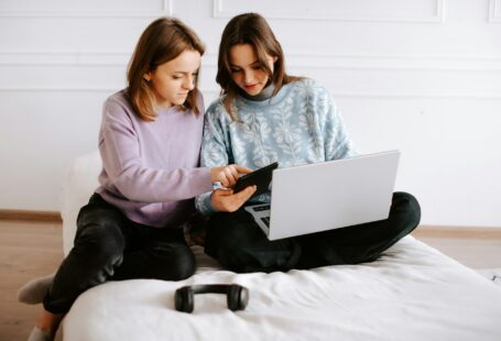 two-girls-sitting-on-a-bed-looking-at-a-laptop